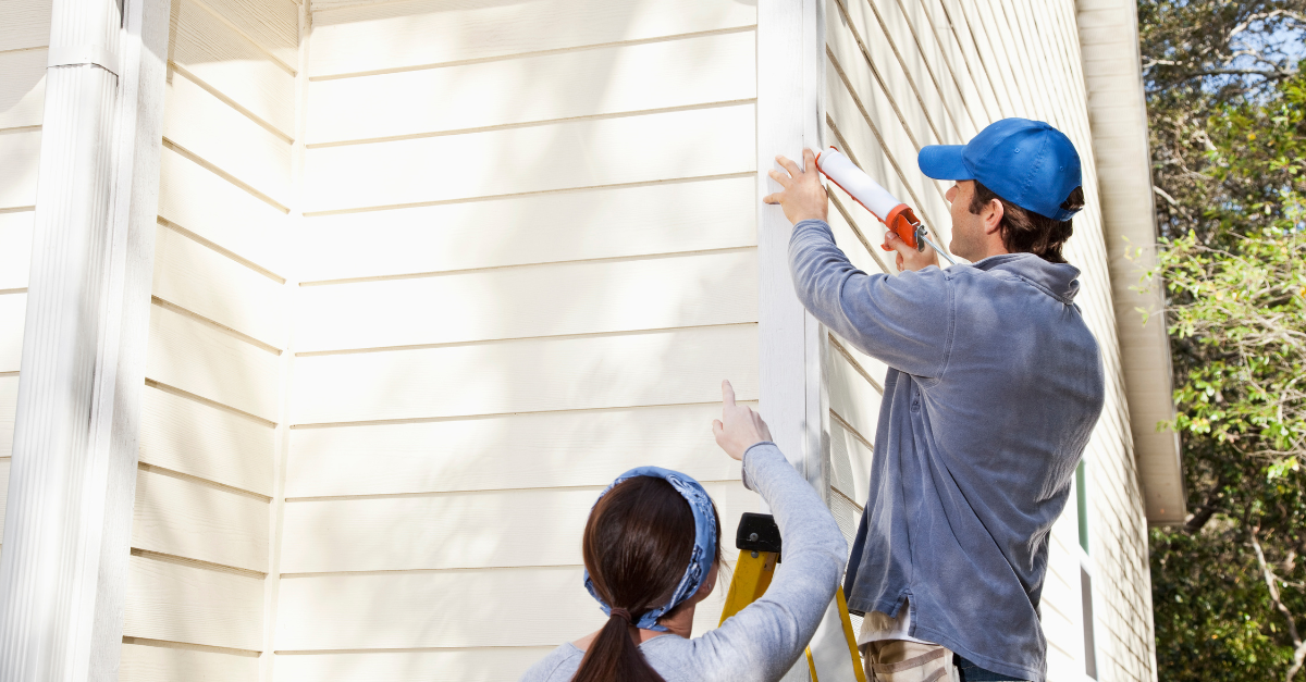 Couple performing maintenance on outside of home